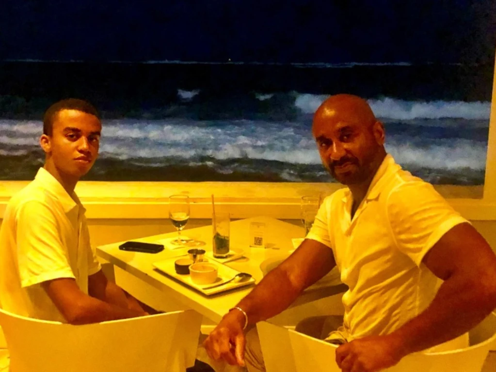 Peter C. Bennett and his son at a seaside restaurant table at night with waves behind them